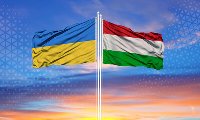 Ukraine and Hungary two flags on flagpoles and blue sky..