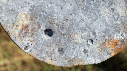 Bullet marks on the steel formed spots and holes deepened.