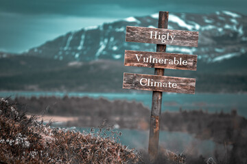 higly vulnerable climate text quote engraved on wooden signpost outdoors in landscape looking polluted and apocalyptic.