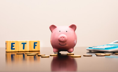 A piggy bank with as initial ETF the word Exchange Traded Fund written on wooden blocks in English...