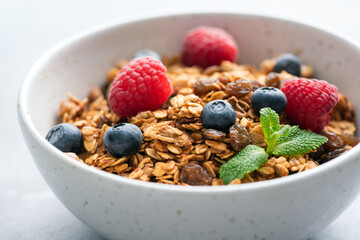 Bowl of crunchy granola with fresh berries, closeup view. Honey oat granola