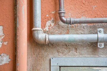 Old water and gas metal pipes fixed in front of a wall