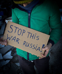A boy holding a 'stop this war russia' banner, a sad image of children suffering from russian aggression on ukraine