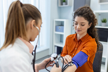 Measuring blood pressure. Young woman have a visit with female doctor in modern clinic. Measuring...