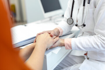 Young female doctor hold hand of caucasian woman patient give comfort, express health care sympathy, medical help trust support encourage reassure infertile patient at medical visit, closeup view.