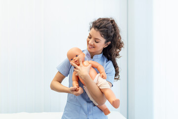 CPR practitioner examining airway passages on infant dummy. Model dummy lays on table and two doctors practice first aid. - obrazy, fototapety, plakaty