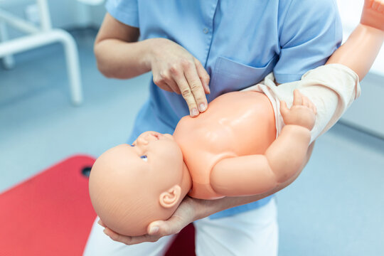 Woman performing CPR on baby training doll with one hand compression. First Aid Training - Cardiopulmonary resuscitation. First aid course on cpr dummy.