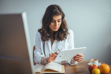 Smiling nutritionist in her office, she is showing healthy vegetables and fruits, healthcare and...