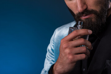 Masculine bearded young man holding a generic bottle of perfume. Male fragrance and perfumery,...