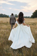 Fototapeta na wymiar Young beautiful couple at sunset in the field