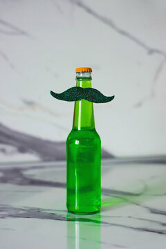 Green beer and lemonade in a bottle with a mustache. St. Patrick's Day. Vertical photo.
