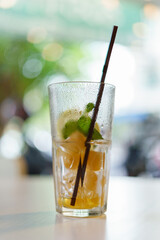 A glass of water that had been drank until there was only ice left inside with a brown straw.