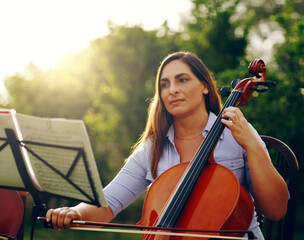 Music is something you hear and feel. Cropped shot of a beautiful woman playing a cello in the backyard. © Lyndon S/peopleimages.com
