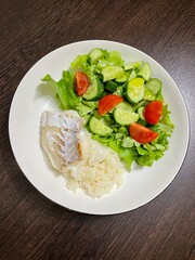 large vertical photo. homemade food. healthy proper nutrition. rice with cod and cherry tomato and cucumber salad. eco.