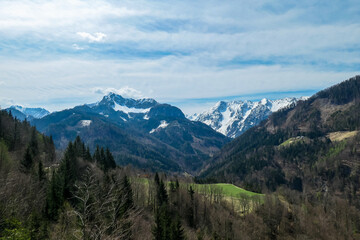Fototapeta na wymiar Scenic view of snow capped mountain peaks of Karawanks near Sinacher Gupf in Carinthia, Austria. Mount Wertatscha and Hochstuhl (Stol) is visible in early spring. Hills in Rosental on sunny day. Hike
