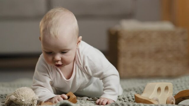 Little girl small boy child kid infant newborn son daughter crawling on carpet on floor home playing with toys with wooden constructor childcare children development orphan adoption health pediatrics