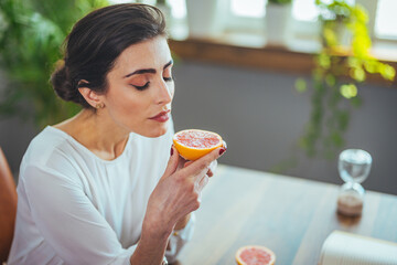 Sick woman trying to sense smell of half fresh orange, has symptoms of Covid-19, corona virus...
