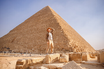 Man tourist with hat and bag walks background of pyramids in Giza Cairo Egypt, sun light travel