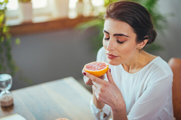 Sick woman trying to sense smell of half fresh orange, has symptoms of Covid-19, corona virus...