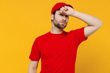 Professional sick ill sad delivery guy employee man in red cap T-shirt uniform workwear work as dealer courier put hand on forehead isolated on plain yellow background studio portrait Service concept