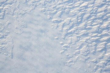 Beautiful winter background with snowy ground. Natural snow texture. Wind sculpted patterns on snow surface.