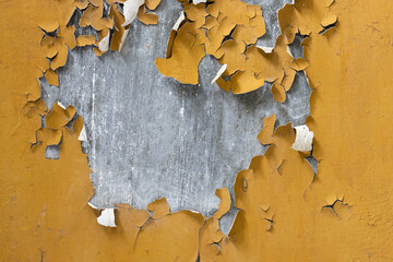 Yellow peeling paint on the wall. Old concrete wall with cracked flaking paint. Weathered rough...
