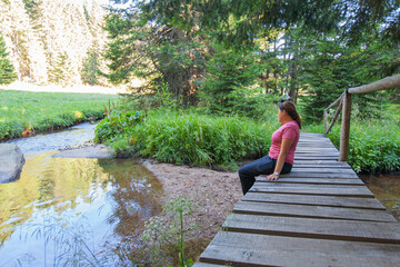 Woman relax by clear water,  mountain forest creek,  on summer day.