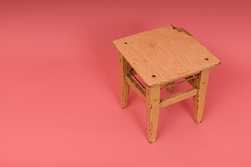 old wooden stool on pink background with copy space