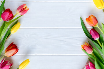 Colorful tulips flower composition over white wooden table background with copy space. Love, Mother's day, Women's day and spring time flower background. Spring nature background.