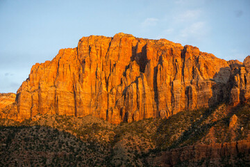 A mountain face glowing orange at sunset.