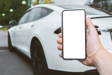 Close-up, Mockup of a smartphone in the hands of a man. Against the background of a white electric car in the city.