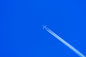 Blue sky with an airplane and a white track behind them. Thematic photography for tourism, airlines and public transport.