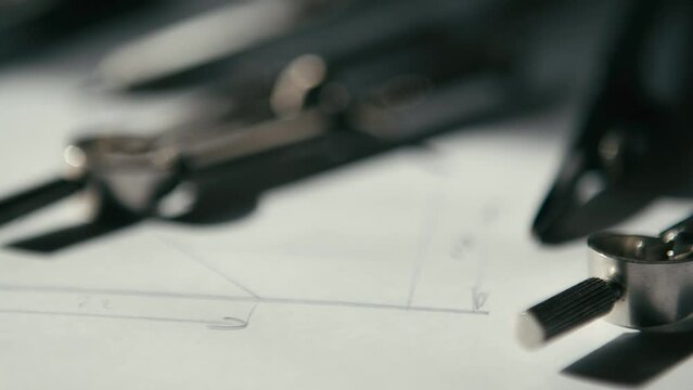 Slow pan and rack focus on the architect's desk, with sketches and compasses.