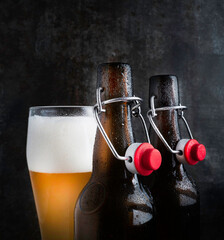 Two bottles of beer with red bugle plugs on a dark gray background .