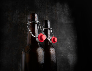Two bottles of beer with red bugle plugs on a dark gray background .