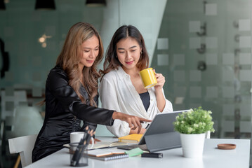 Two young Asian businesswoman discuss with new startup project Idea presentation, analyze planning and financial statistics and investment market on laptop computer at office.