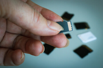 MicroSD memory card in hand against a blurred background of other SD memory cards.
