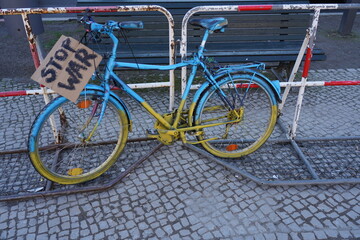 Fahrrad in den Nationalfarben der Ukraine mit einem kleinen Plakat "Stop War" in Berlin