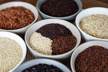 Set of colorful collection of rice and quinoa grains of different colors: white, red and black in bowls.