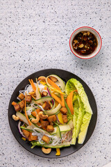 Rice noodle salad with tofu, fresh vegetables and cashew nuts with spicy sauce. Vietnamese cuisine, top view.