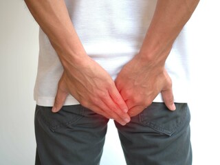 Hemorrhoids in man and hand holding him bottom on white background for health care concept. closeup photo, blurred.
