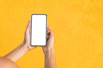 Close-up, Mockup of a smartphone in the hands of a girl. Against the background of a yellow facade made of decorative plaster.