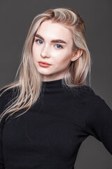 Portrait of a young blonde woman on dark background