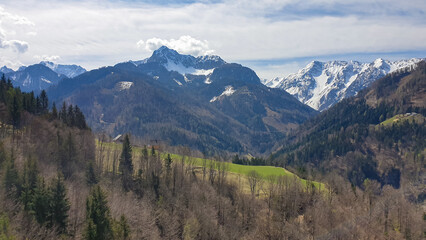 Fototapeta premium Scenic view of snow capped mountain peaks of Karawanks near Sinacher Gupf in Carinthia, Austria. Mount Wertatscha and Hochstuhl (Stol) is visible in early spring. Hills in Rosental on sunny day. Hike