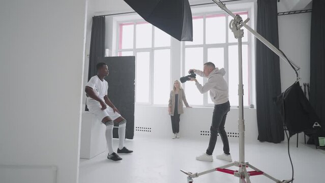 photographer is capturing professional football player with ball in studio, content for magazine