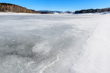 Winter landscape by the frozen lake with hills in the background background. Frozen Lake on a cold winter day