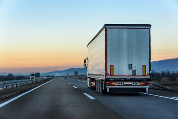 White Transportation Truck on a highway road under blue sunrise sky