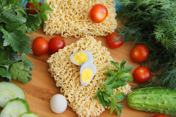Instant pasta with fresh vegetables on a wooden background