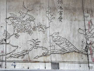 Macau, Island of Macau, China - September 19 2019: detail of bird and tree art, with chinese writing, in wood