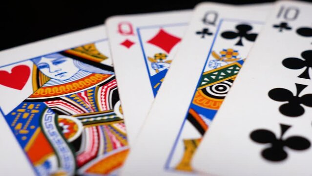 Camera pans across cards arranged as a full house hand in poker, white cards against a black table, card games concept